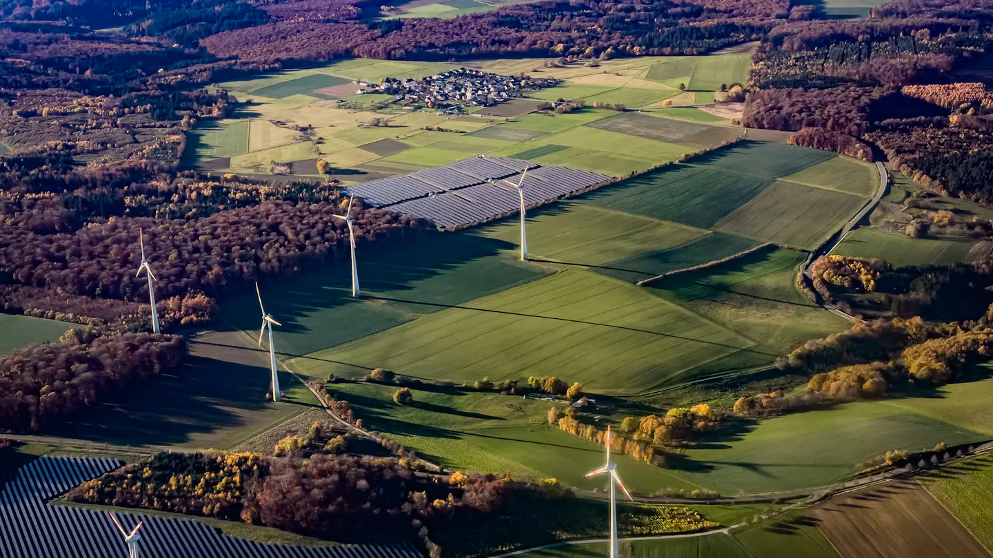 Aerial view of wind turbines and solar arrays across farmland